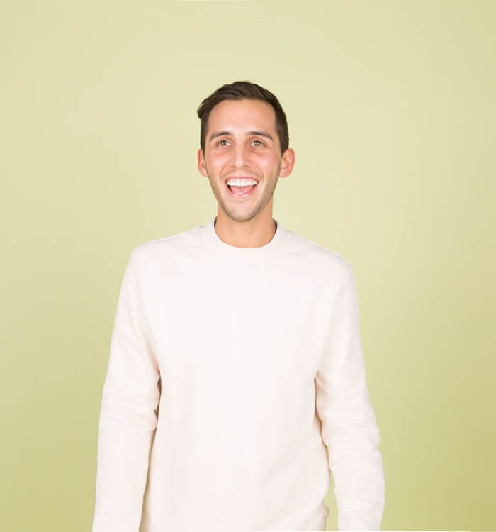 team5 Photographic image depicting a smiling man in a white sweater, against a pale green background